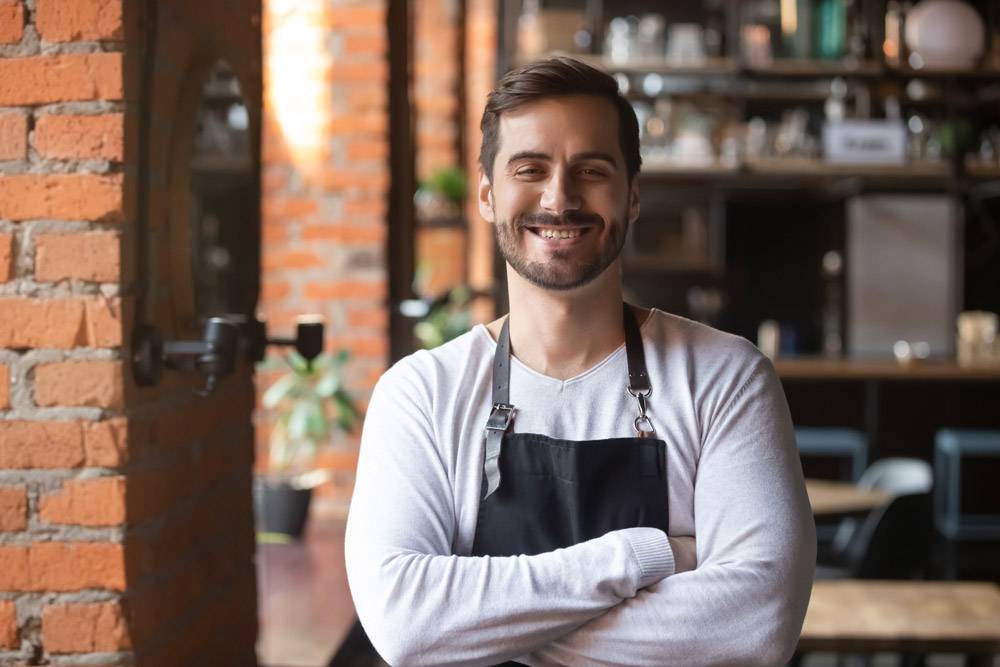 Man in apron smiling. Hospitality industry background check concept.